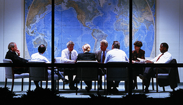 Group of coworkers gathered in suits around a table in a meeting room