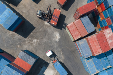 Birdseye view of container shipyard with a forklift and freight truck