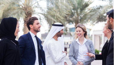 An Emirati businessman and businesswoman having a conversation with Western businessmen and businesswomen 